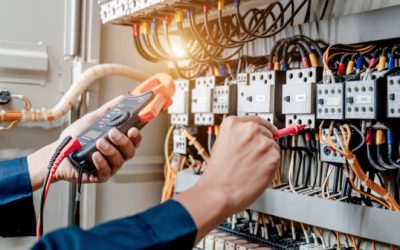 Electrician engineer uses a multimeter to test the electrical installation and power line current in an electrical system control cabinet.